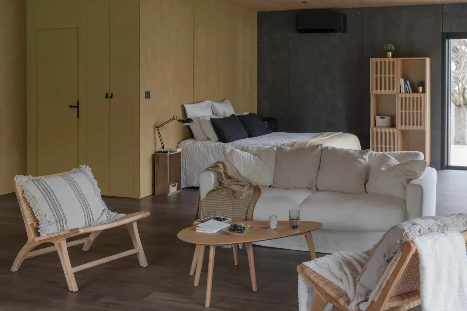 Studio in the gîte at La Maison des Monts d'Or: bed, white sofa, wooden armchairs and shelving