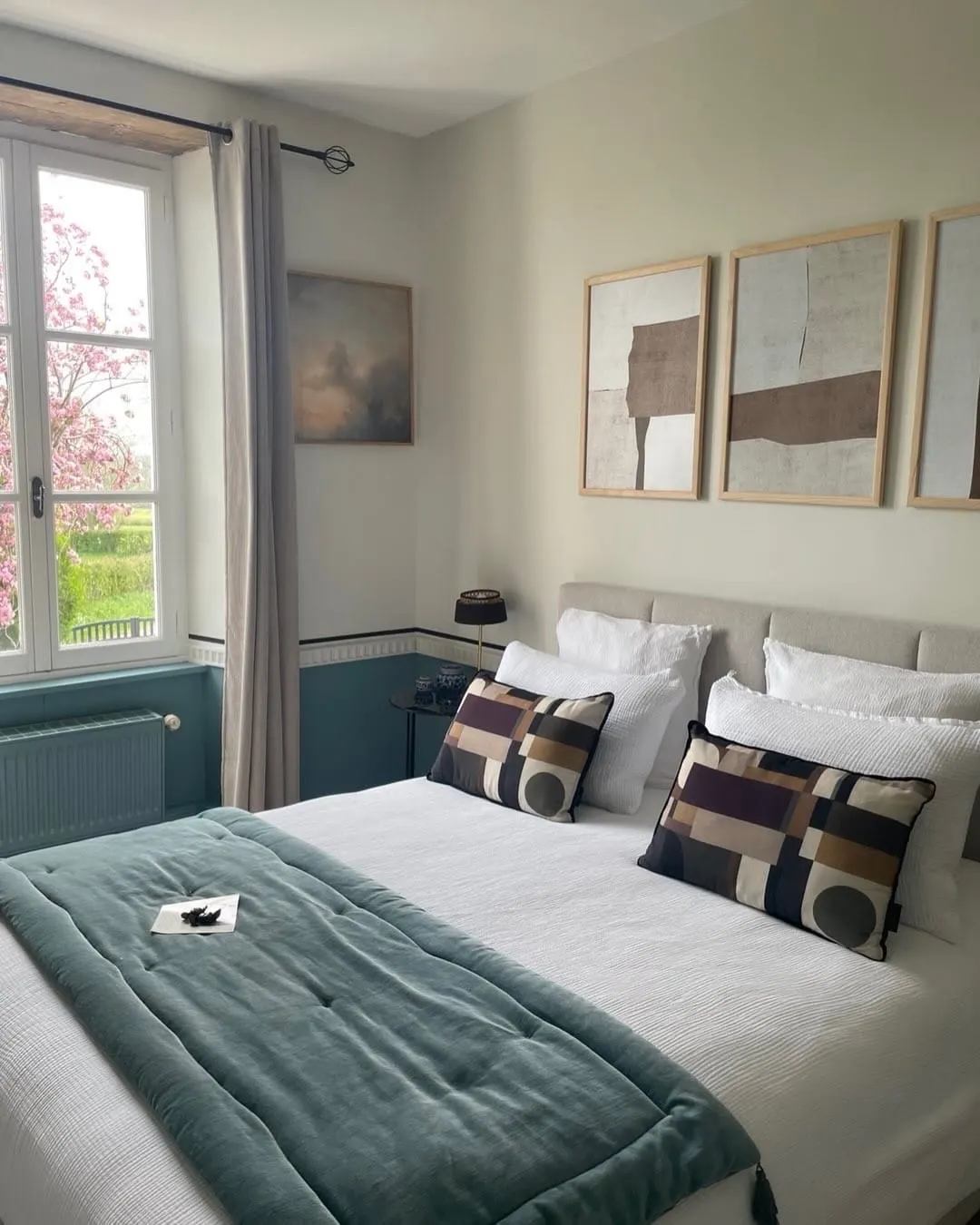 Honfleur room at Domaine de Marculfo, white bed, green throw, graphic cushions and window onto the garden