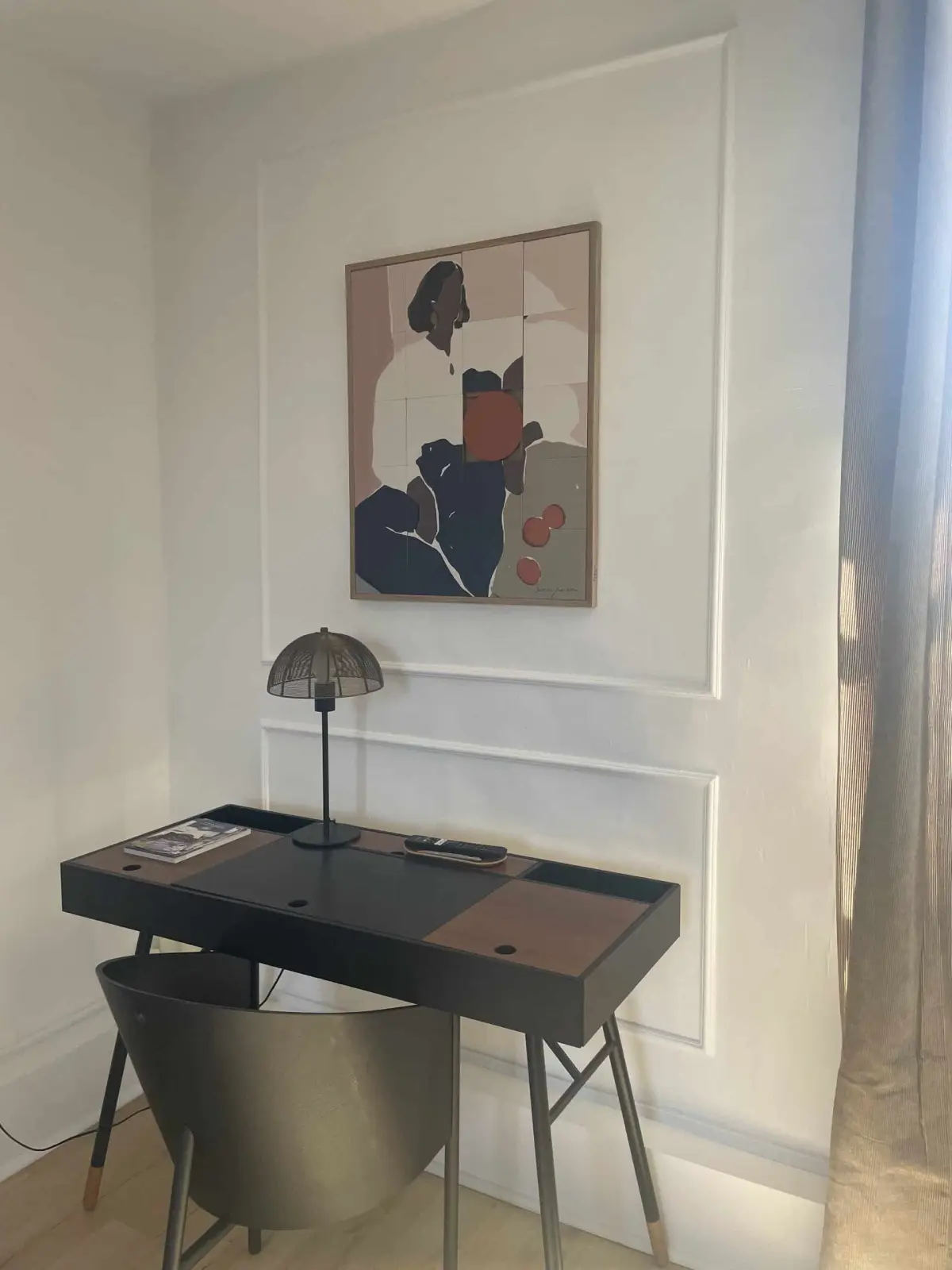 Desk corner in the Deauville room at Domaine de Marculfo, black desk, lamp and painting on a panelled wall