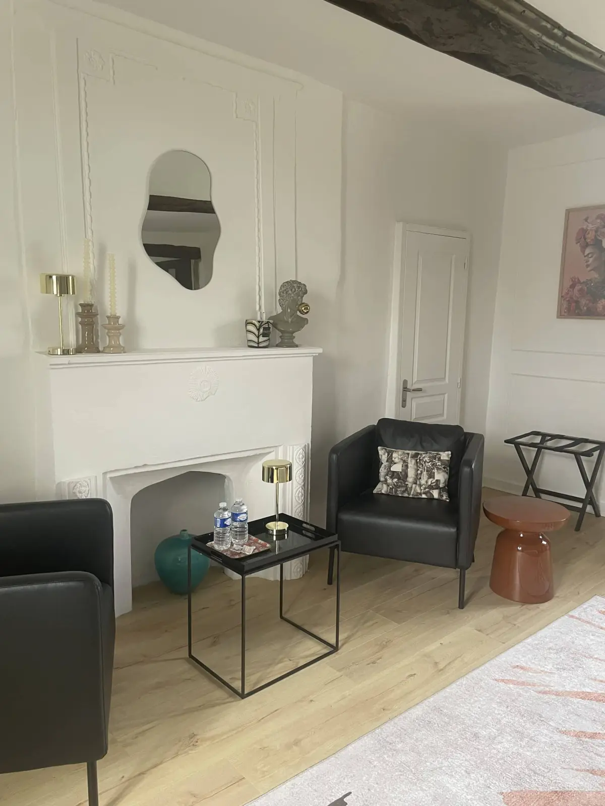 Sitting area of the Deauville room at Marculfo, white fireplace, black armchairs, coffee table and mirror