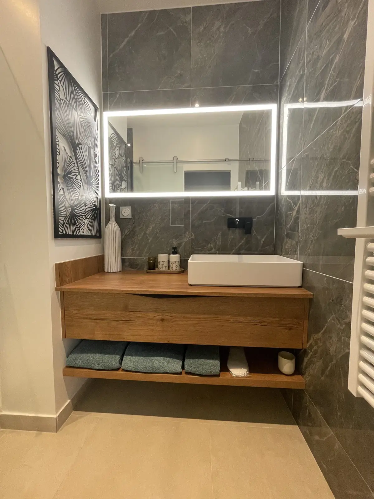 Bathroom of the Deauville room at Marculfo, basin on a wooden unit, illuminated mirror and grey tiles