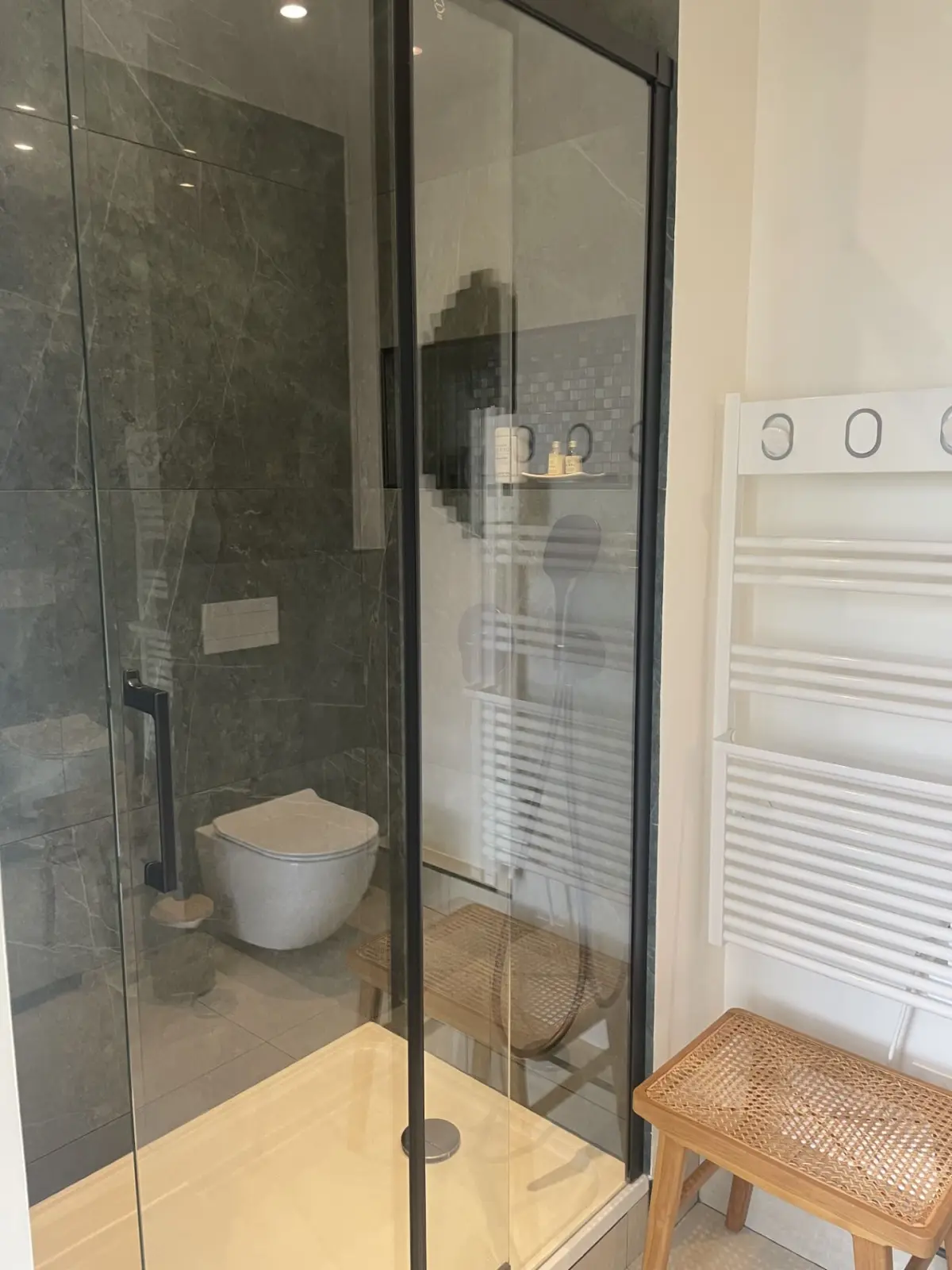 Shower room of the Honfleur room at Marculfo, glass shower, wall-hung toilet, towel rail and stool