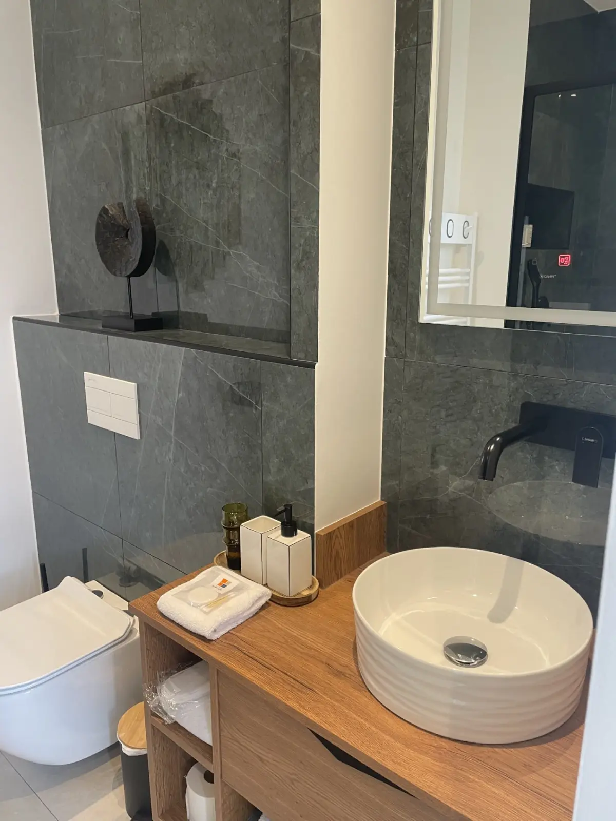 Bathroom of the Honfleur room at Marculfo, round basin on a wooden unit and grey tiles