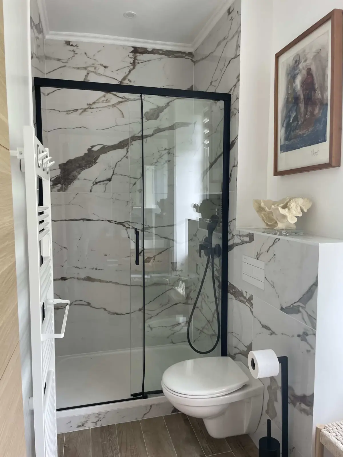 Shower room of the Houlgate room at Marculfo, glass shower with white marble-effect tiles and wall-hung toilet