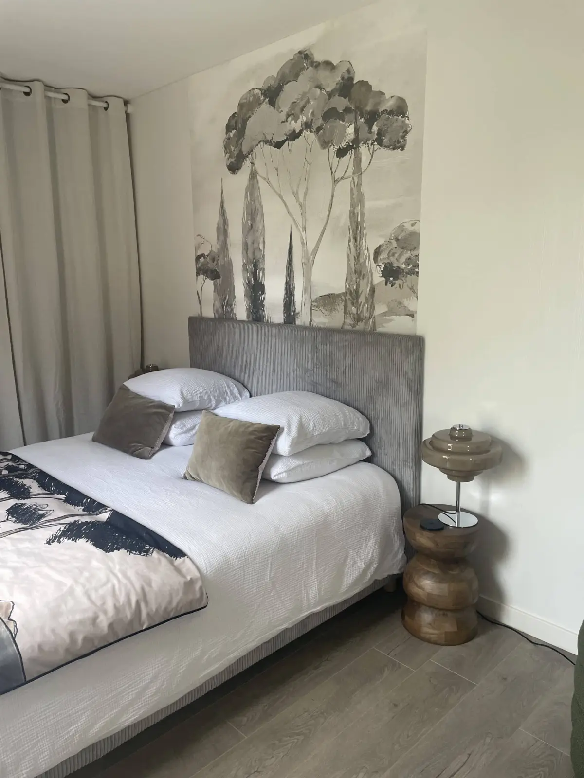 Lodge bedroom at Domaine de Marculfo, grey velvet headboard, pine-tree wallpaper and wooden bedside table