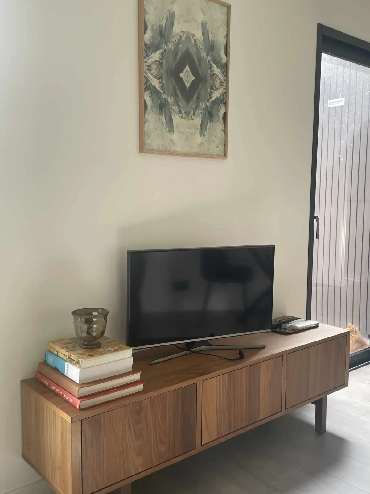 Lodge living room at Domaine de Marculfo, wooden TV unit, stacked books and green-toned painting