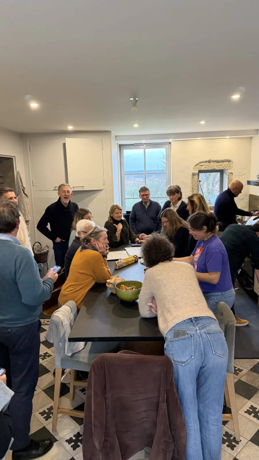 Network members gathered round a table in a kitchen with black and white floor tiles