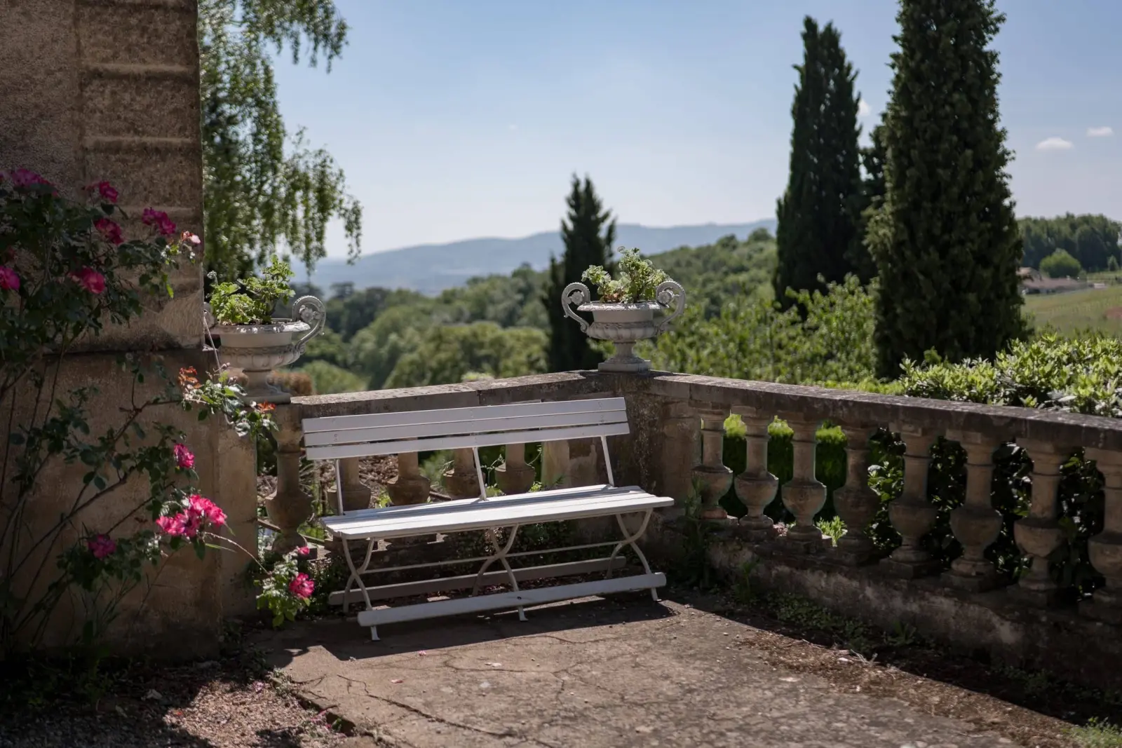 Balustraded terrace at Domaine de Montclair with a white bench and a view of wooded hills