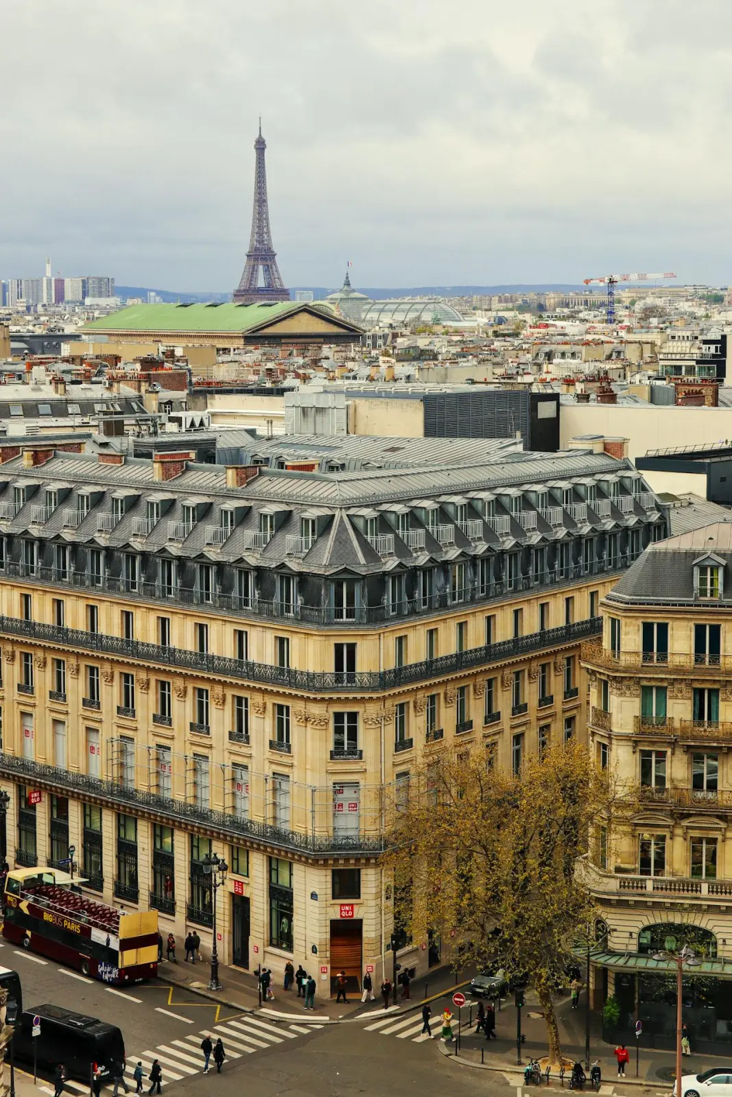 Paris vu des toits : immeubles haussmanniens, carrefour animé et tour Eiffel à l'horizon