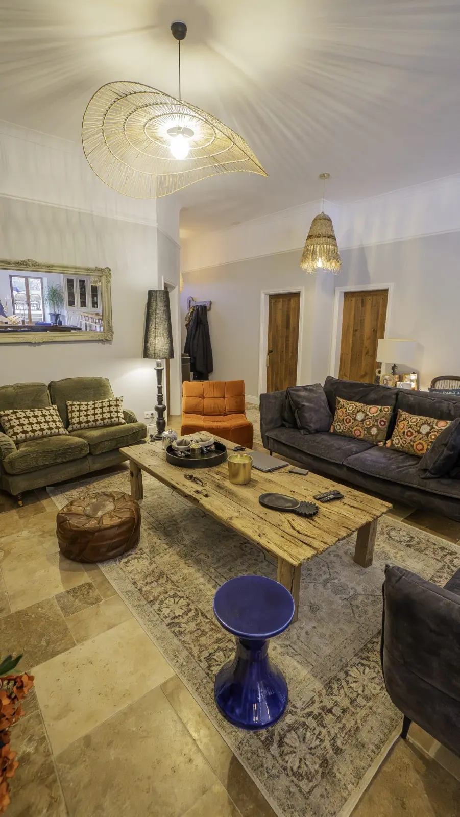 Lounge at Le Patio Bleu with sofas, rough wood coffee table, rug, leather pouffe and rattan pendant light