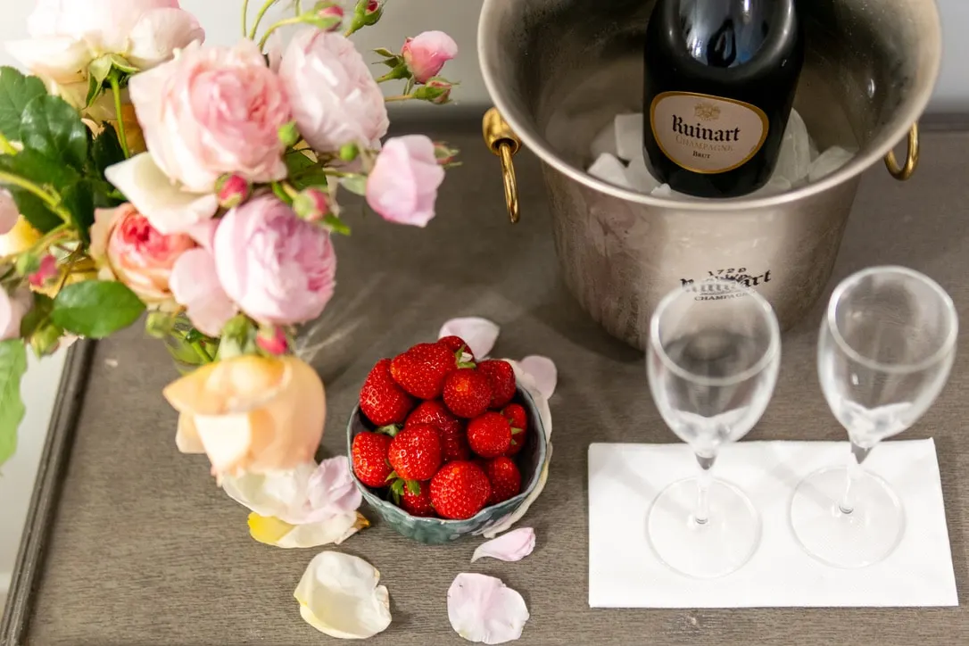 Champagne in an ice bucket, two flutes, a bowl of strawberries and garden roses, La Plonplonière