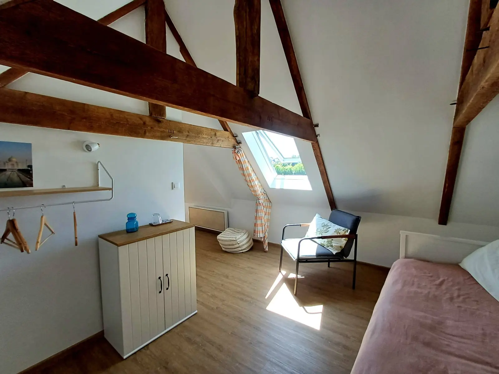 Cocotte room at Ty Monde under exposed beams, armchair by the skylight, white cupboard and bed