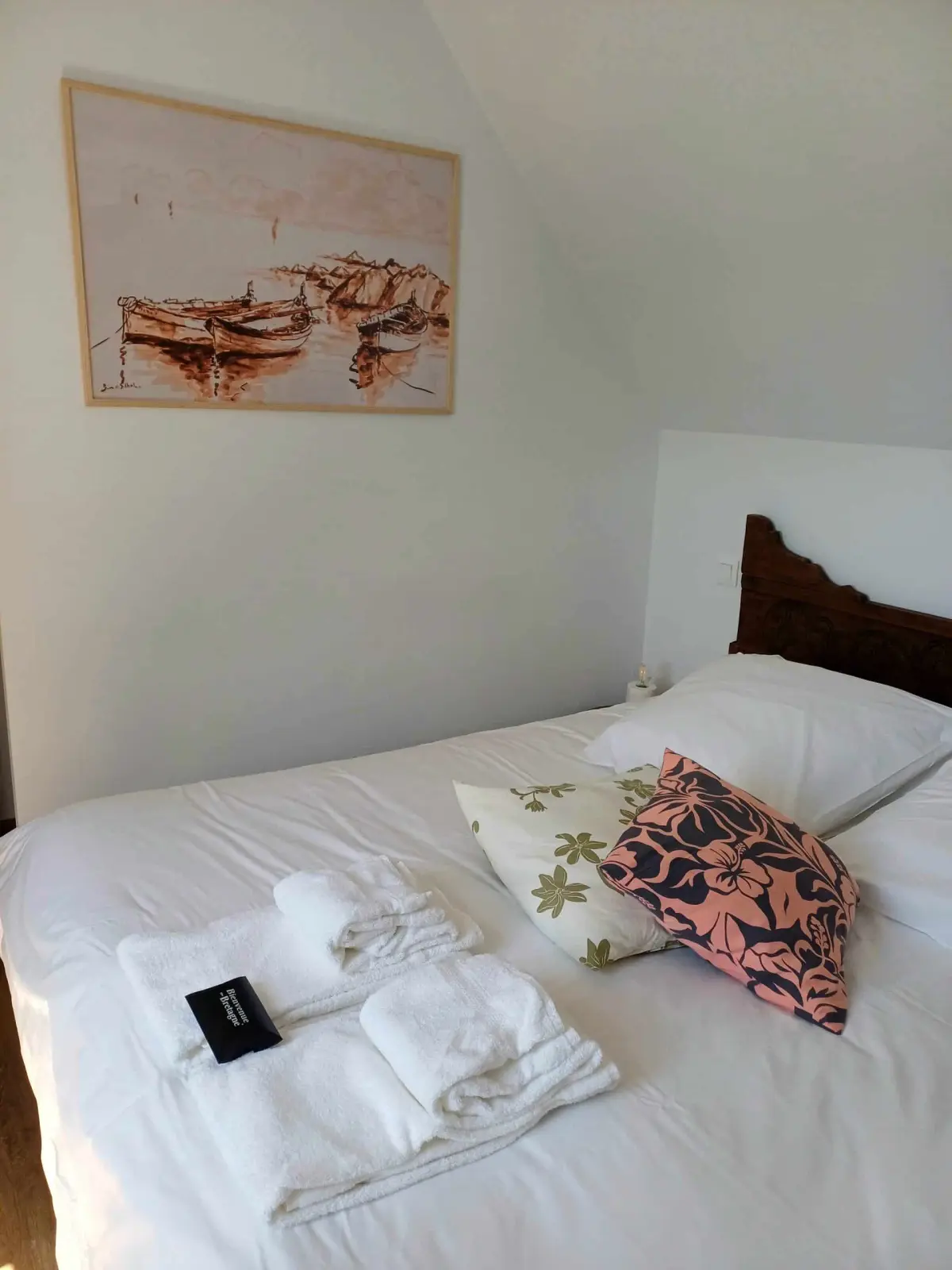 Cocotte room at Ty Monde: bed with folded towels, floral cushions and a drawing of boats on the wall