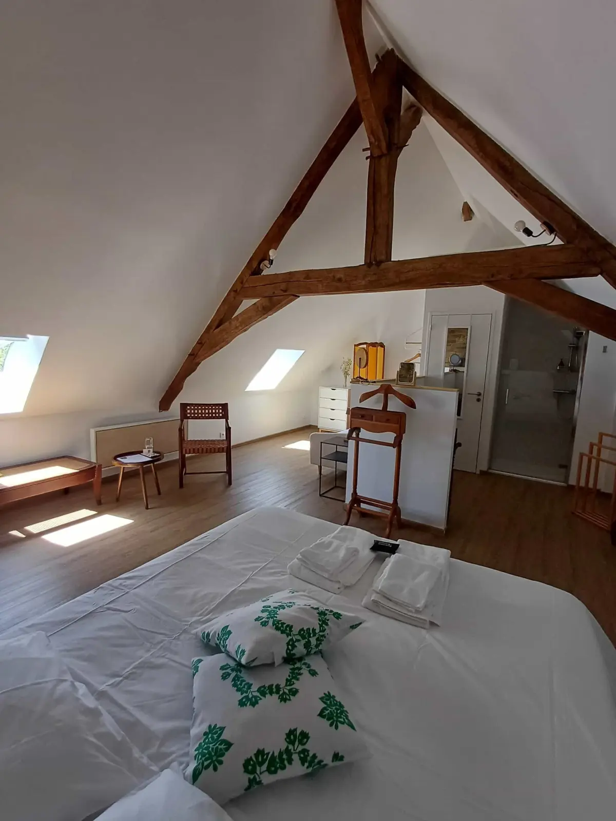 Insoupçonnée room at Ty Monde: large bed under the roof beams, skylights, wooden valet stand and shower room
