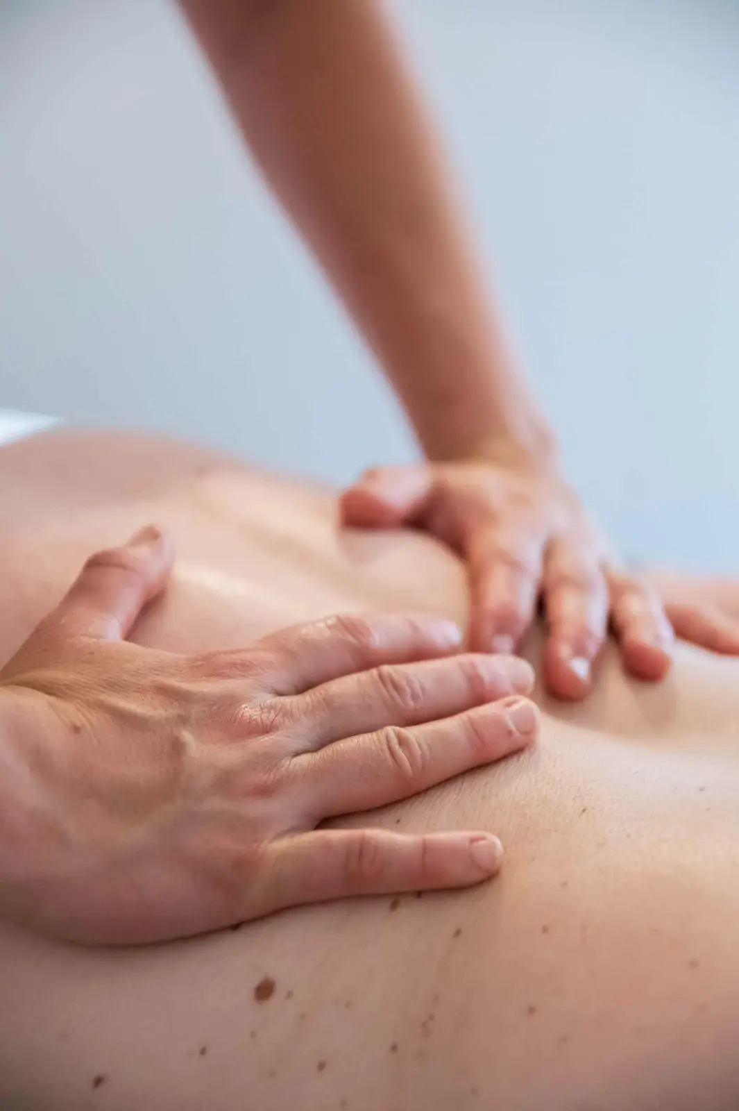 Mains d'une praticienne massant le dos d'une personne allongée, chez Ty Monde