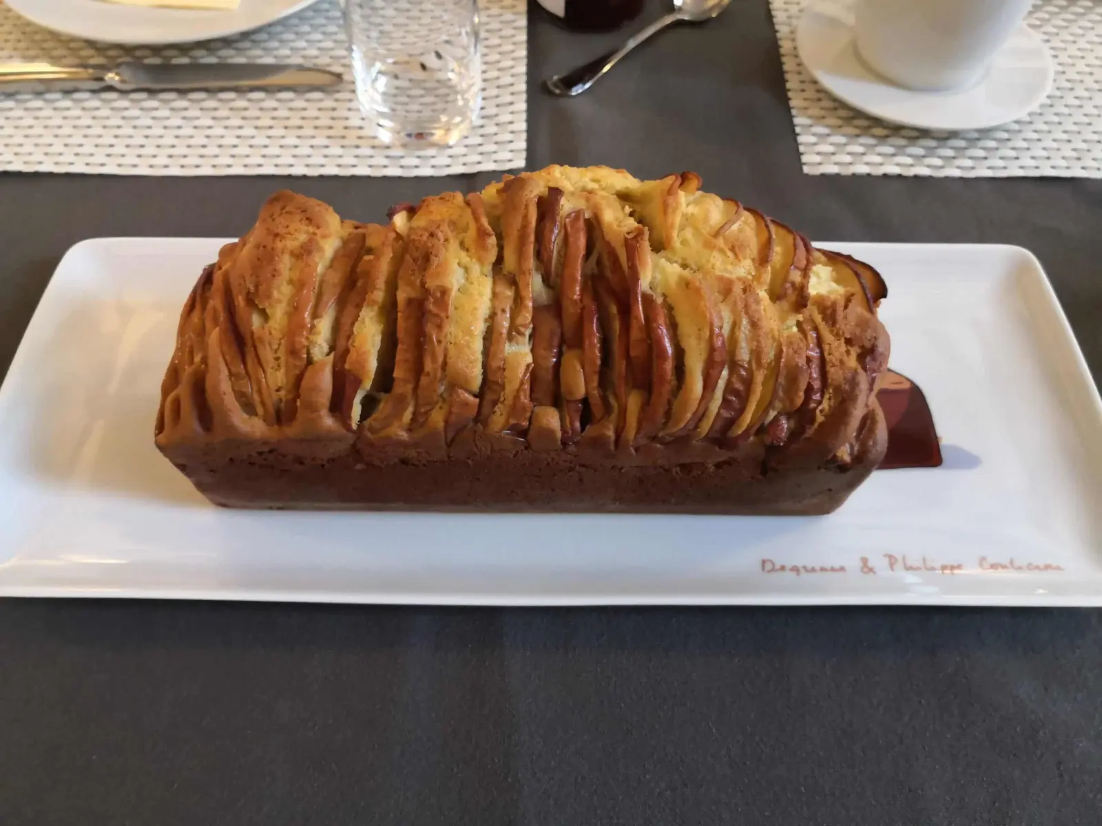 Layered pull-apart brioche loaf on a white rectangular dish, breakfast table at La Vie Voyage